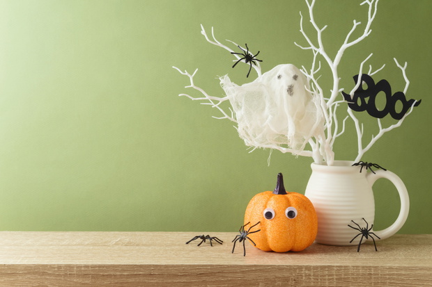 Halloween holiday decorations with glitter pumpkin, spiders and ghost on wooden table.