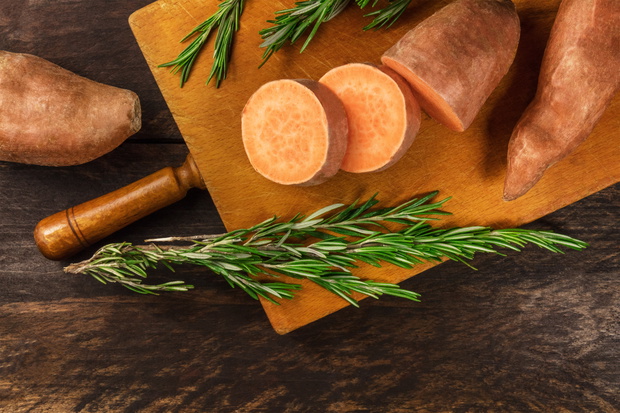 Slices of sweet potatoes with fresh rosemary and copyspace