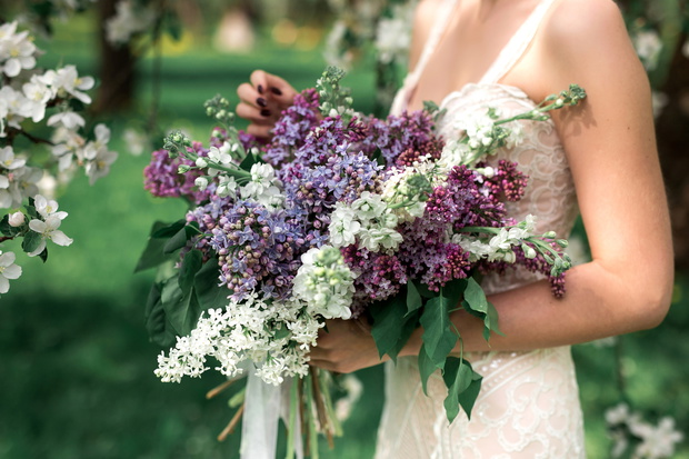 The bride is holding a wedding bouquet of lilacs.