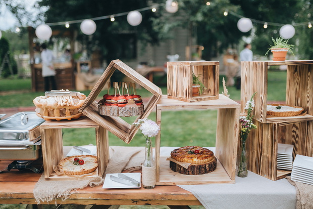 on decorated buffet table in wooden boxes are cakes and snacks