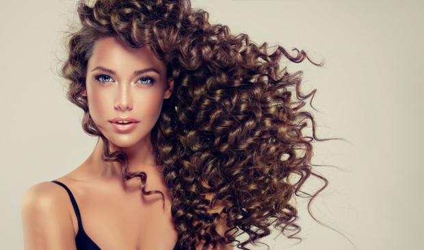 Brunette girl with long and shiny curly hair . Beautiful model w