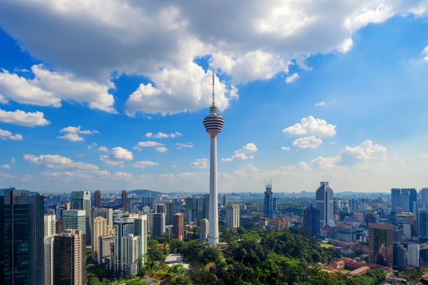 Menara Kuala Lumpur Tower with clouds sky. Aerial view of Kuala Lumpur Downtown, Malaysia. Financial district and business centers in urban city in Asia. Skyscraper and high-rise buildings at noon.