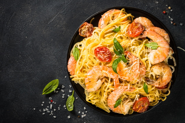 Pasta seafood with shrimp on black table.