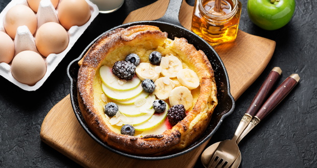 Dutch baby pancake with apples, banana, fresh berries powdered sugar and almonds.