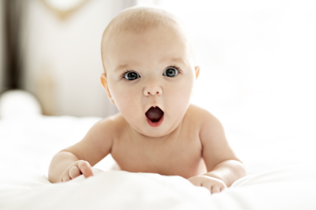 A Cute baby girl on a white bed at home yawn