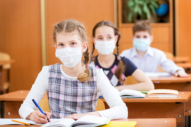 schoolkids with protection mask against flu virus at lesson
