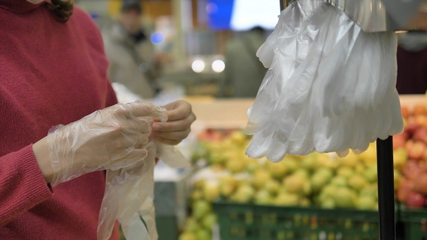 Coronavirus pandemic. A woman in a supermarket puts on disposable plastic gloves to protect against coronavirus, close-up.