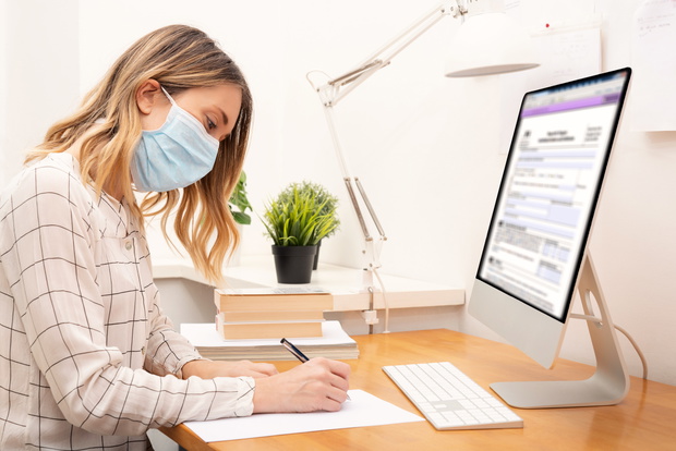 Young business woman working from home, wearing protective mask