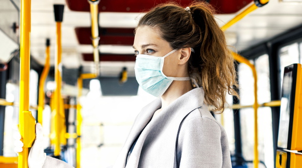 Woman wearing surgical protective mask in a public transportation