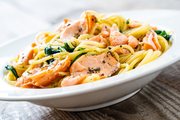 Pasta with salmon and spinach on wooden background