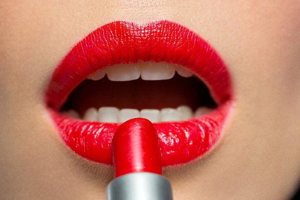 close up of woman applying red lipstick to lips