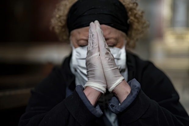 Senior woman in gloves and mask praying in a church