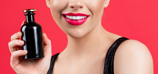 Beautiful girl using perfume. Woman with bottle of perfume. Woman presents perfumes fragrance. Woman perfumes bottle. Sexy lips. Red lip
