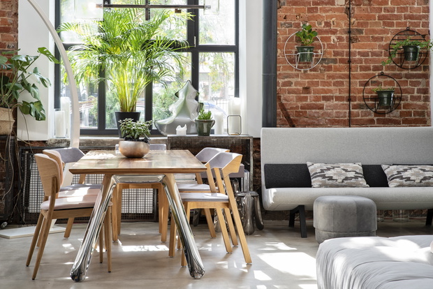 Industrial bright interior of living room in loft apartment in modern style. Bricky wall, big window and wooden table in scandinavian style.