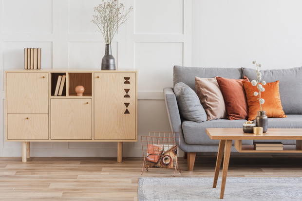 Wooden furniture and grey scandinavian sofa with pillows in beautiful living room interior