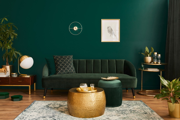 Luxury living room in house with modern interior design, green velvet sofa, coffee table, pouf, gold decoration, plant, lamp, carpet, mock up poster frame and elegant accessories. Template.