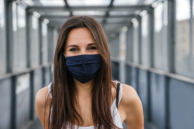 Portrait of beautiful woman on iron bridge in the summer in the city with face mask for protection from contagion by Coronavirus, Covid-19 - Millennial looking and smiling - Concept of naturalness