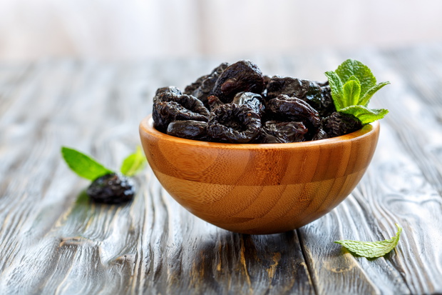 Prunes and mint in a wooden bowl.
