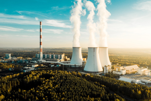 A Power plant with white smoke over it's chimneys