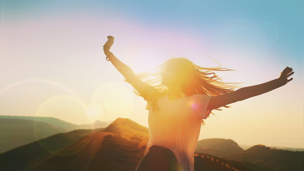 Girl on a background of mountains joyful spread her arms dancing at a height