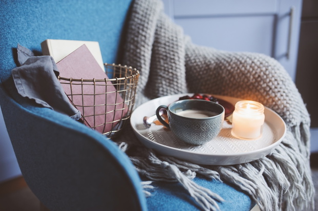 Cozy winter weekend at home. Morning with coffee or cocoa, berry pie, books, warm knitted blanket and nordic style chair. Hygge concept.