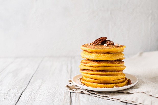 Stack of pancakes with pecan and syrup in nordic style