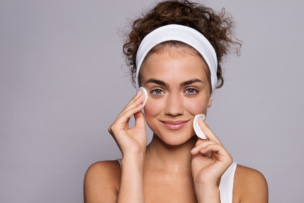 Portrait of a young woman cleaning face in a studio, beauty and skin care.