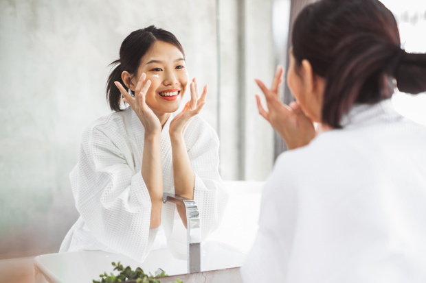 Asian woman cleaning face front of mirror, skin care and cosmeti