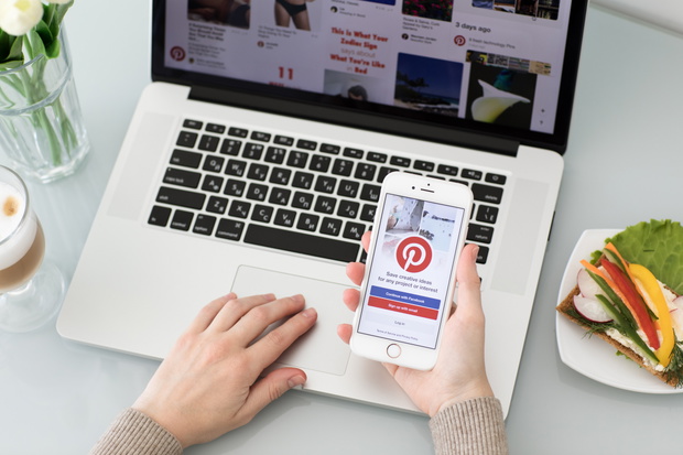 Woman hand holding iPhone with social Internet service Pinterest