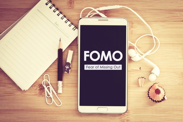 FOMO , Fear of missing out text on  Smart phone with a Blank not