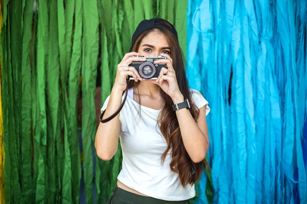 young beautiful woman holding retro film camera to take photogra