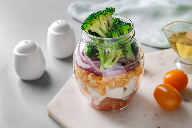 Healthy salad in glass jar on light grey table