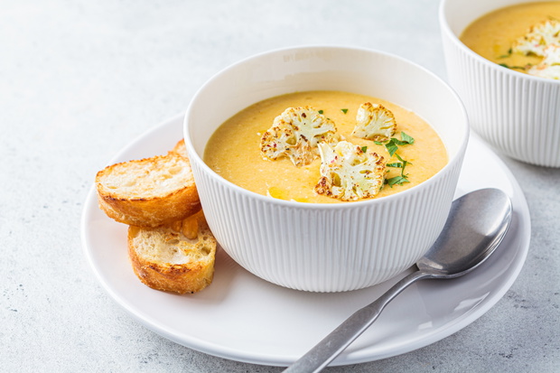 Vegetarian cream cheese soup with cauliflower in white bowl. Hea