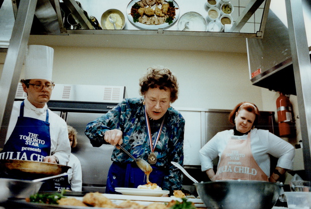 By the Book: Top, Julia Child visits Marion Kane at her home. Above, at demo, Child puts finishing t