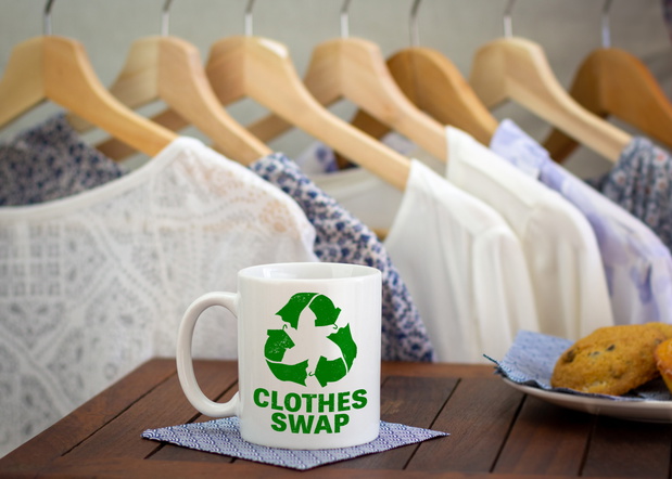 Clothes swap icon and text on mug in front of clothes at swap pa