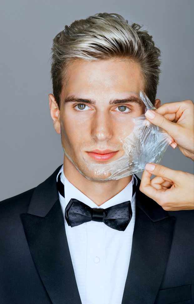 Portrait of well dressed elegant man in facial mask on gray back