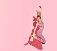 Happy athletic woman jumping in silhouette. Photo of sporty woman in fashionable pink sportswear on pink