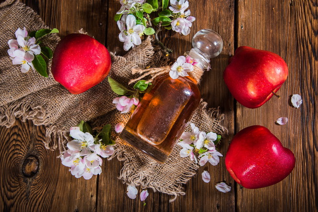 A bottle of apple cider vinegar (cider), fresh apples and apple-