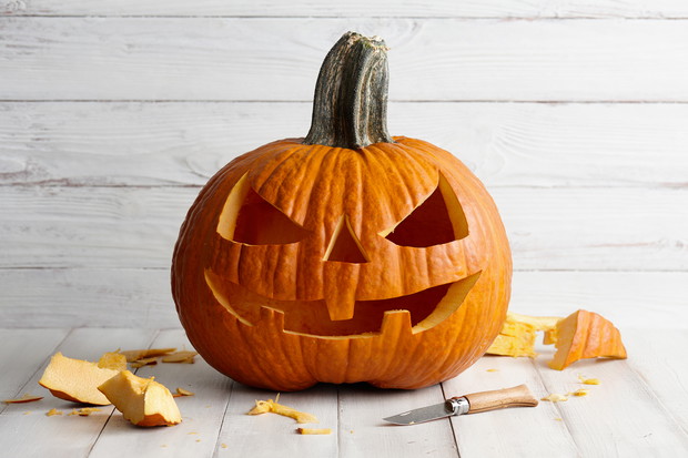 Carved Halloween pumpkin on white boards, holiday decorations
