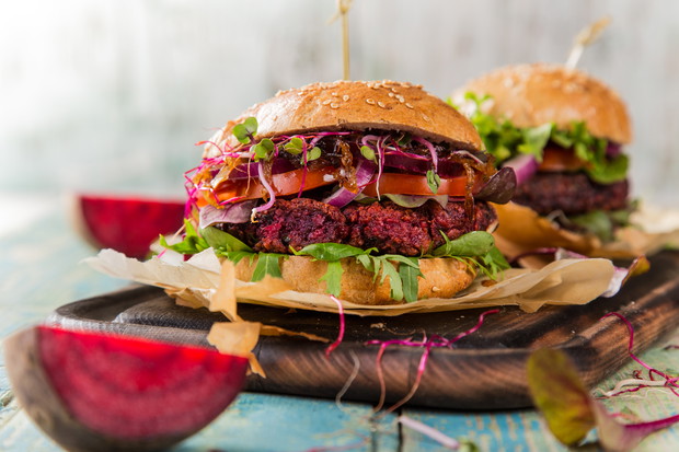 Tasty vegetarian beet burgers on wooden table.