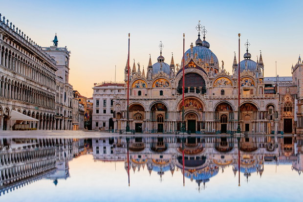 Sunrise in San Marco square with Campanile and San Marco's Basilica. The main square of the old town. Venice, Veneto Italy. Reflection on the flooded square.