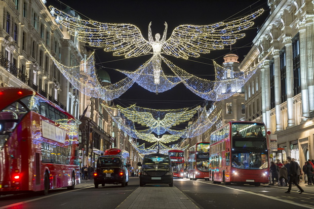 Red double-decker buses pass under twinkling Christmas lights along the upscale shopping district of Regent Street.