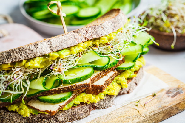 Big veggie sandwich with tofu, vegetables, sprouts and guacamole. Healthy vegan food concept.