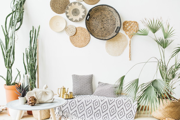 Modern minimal home interior design. Pillows, golden teapot, decorative straw plates, Scandinavian blanket, tropical palm tree, succulent and decorations.