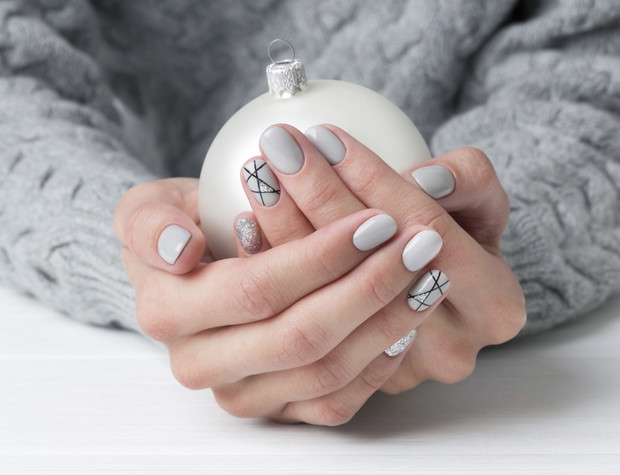 Woman's hands with geometric manicure nail design in cozy sweater