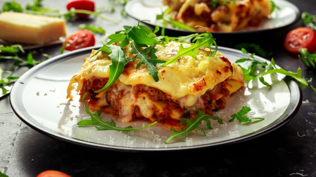 Homemade lasagna with minced beef bolognese and bechamel sauce topped wild arugula, parmesan cheese