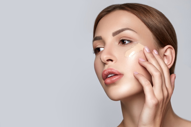 Woman applying foundation. Skin tone cream lines on woman face.