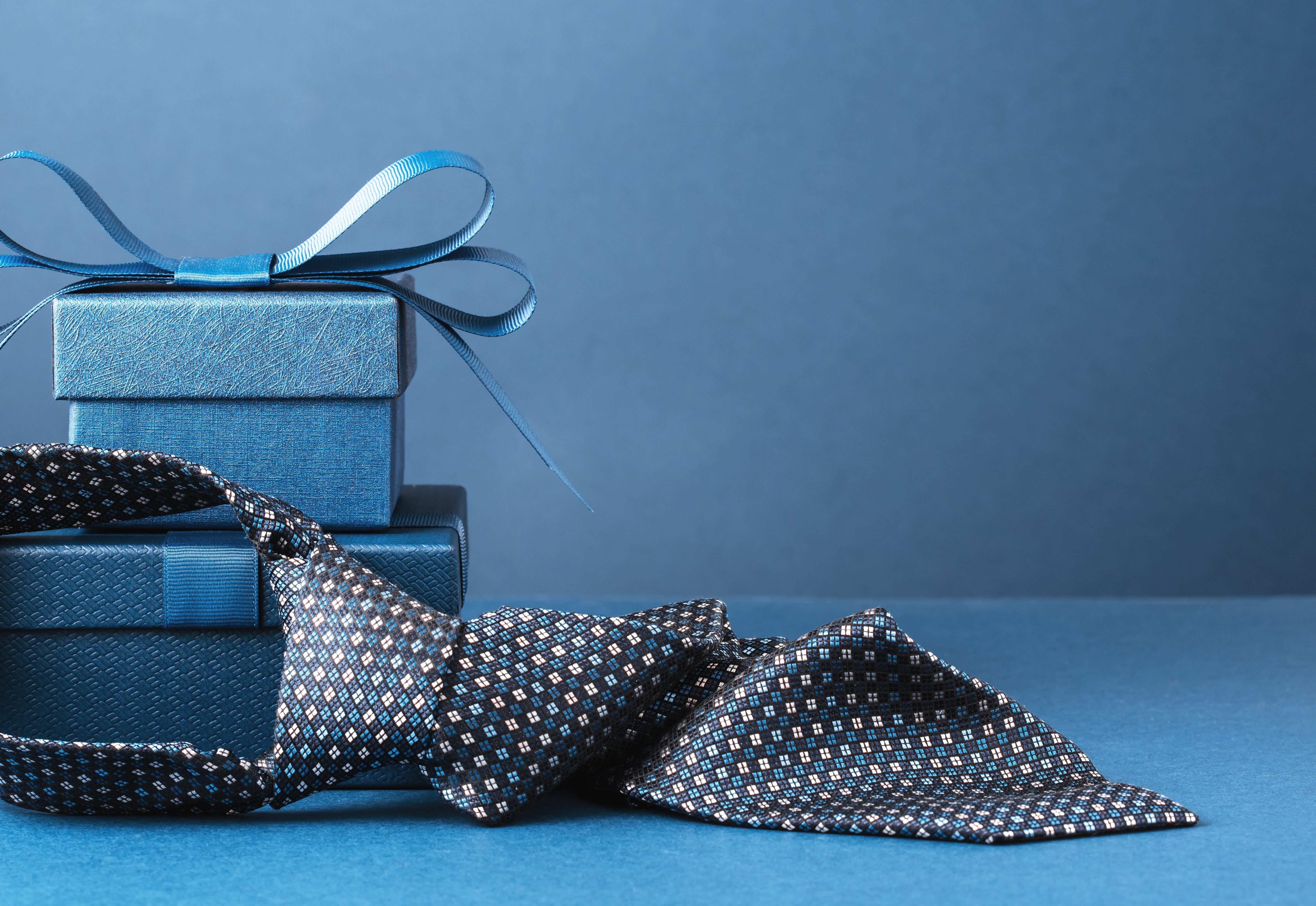 Happy Fathers Day background. gift box and necktie on blue table.