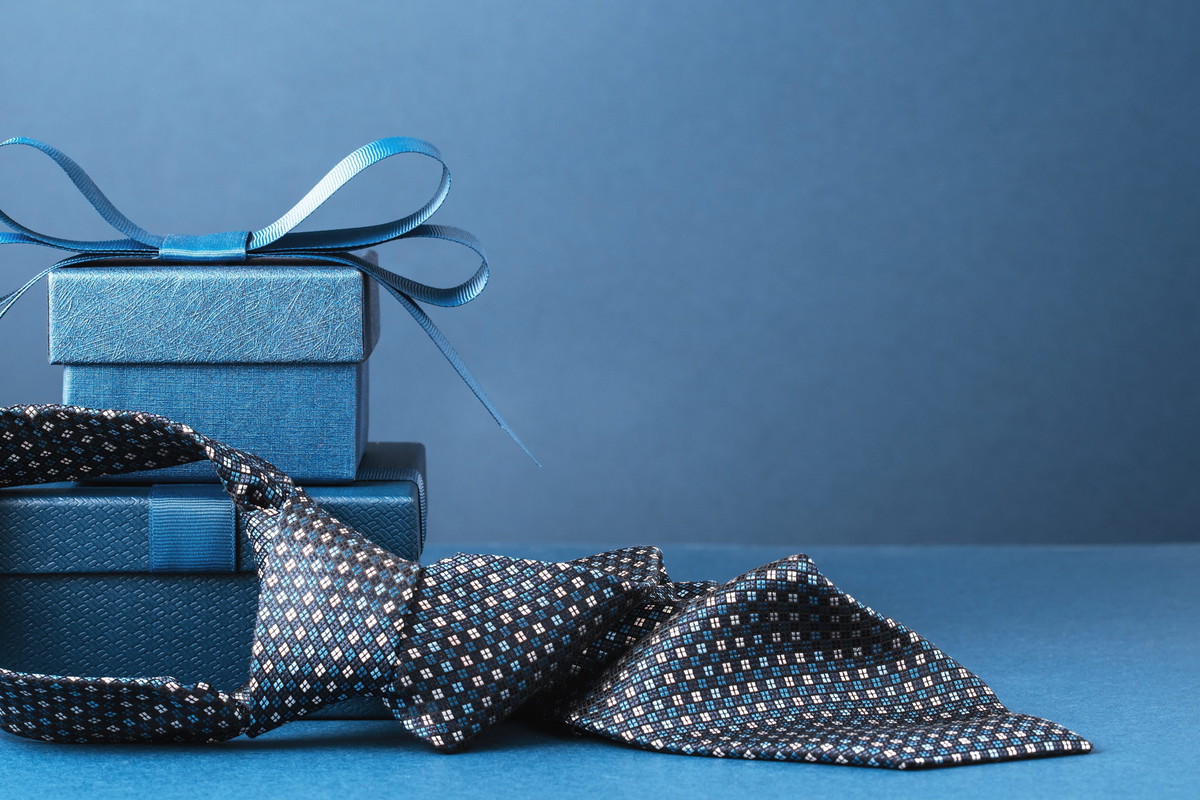 Happy Fathers Day background. gift box and necktie on blue table.