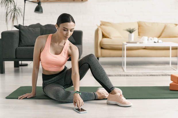 Woman using smartphone during home workout stock photo